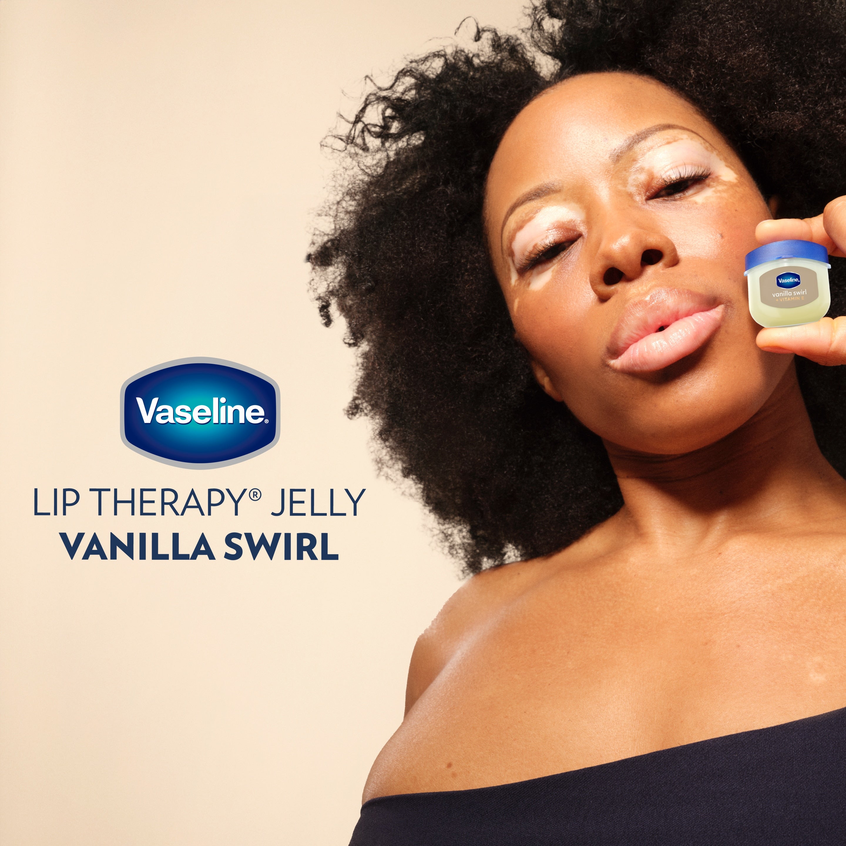 A model holds a Vaseline® Lip Therapy® Vanilla Swirl Mini next to her face